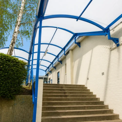 Bespoke covered walkway canopy providing sheltered access to a school building and external staircase