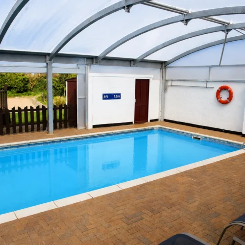 Bespoke pool enclosure canopy creating a bright, weather-protected indoor swimming environment