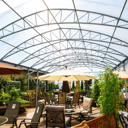 Large-span garden centre canopy creating covered retail space for outdoor furniture, plants and seasonal displays